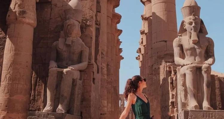 Woman posing near large statues in Luxor.