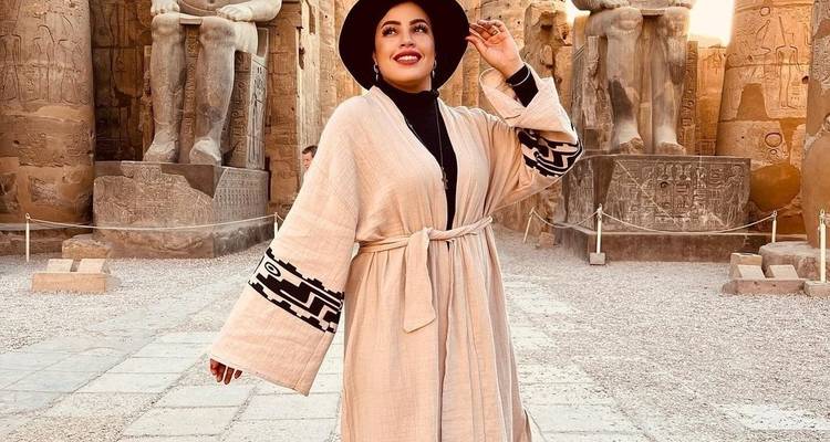 Fashionable woman standing among Egyptian ruins.