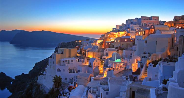 Vue panoramique d'une ville côtière avec des bâtiments et coucher de soleil.