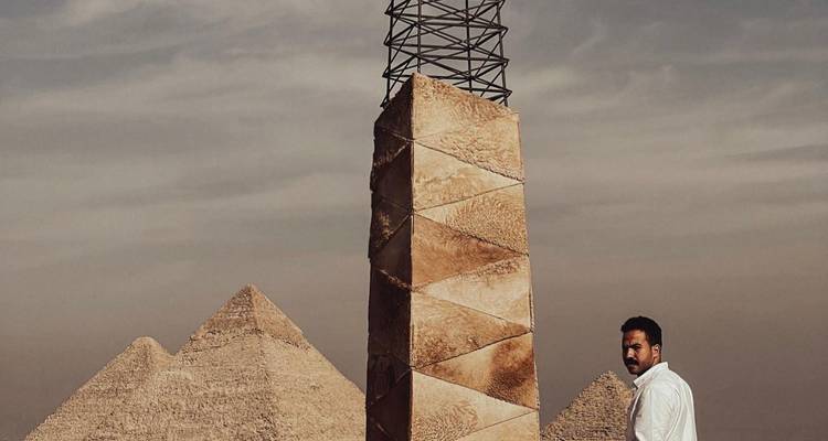 Homme debout près d'une installation d'art moderne avec les pyramides en arrière-plan, Le Caire.
