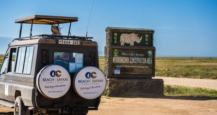 Véhicule de safari garé à côté du panneau de la zone de conservation du Ngorongoro.