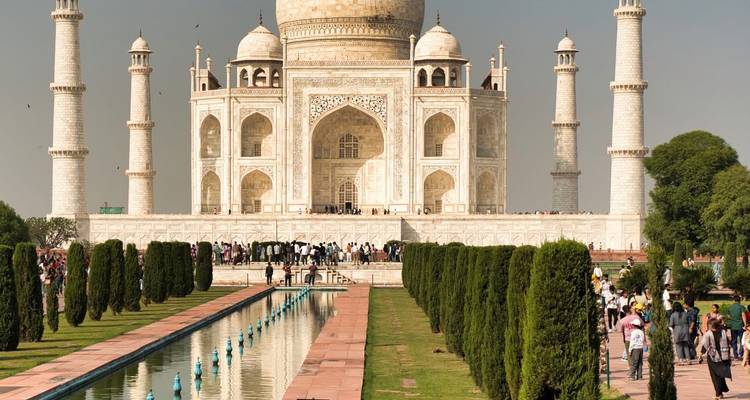 Front view of the Taj Mahal with reflecting pool, gardens, and crowds of visitors on a sunny day