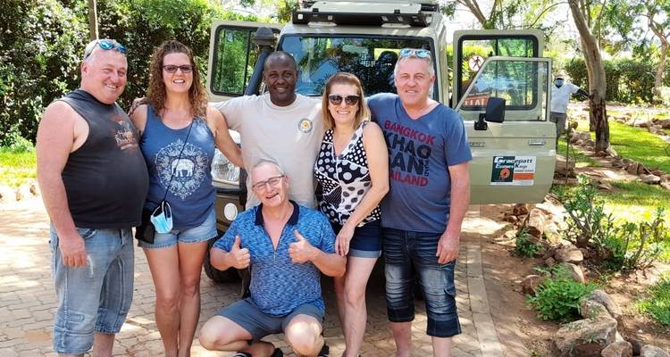 Gruppe von Menschen, die mit einem Safari-Fahrzeug posieren.