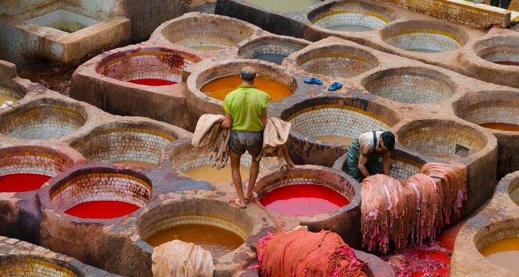 Workers in a traditional dyeing pit dealing with colorful materials.