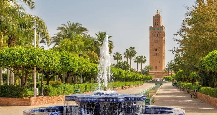 Beautiful park scene with a fountain and tall minaret in the background.