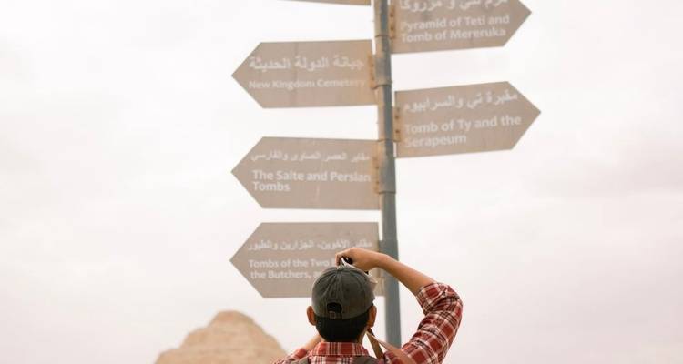 Personne photographiant un panneau avec des pyramides en arrière-plan.