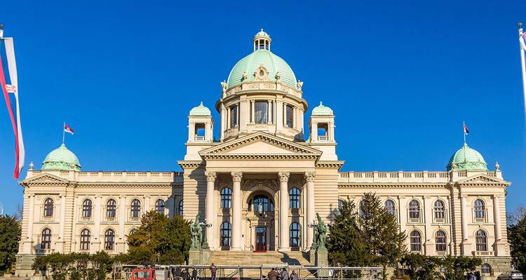 La Asamblea Nacional neoclásica de Serbia se alza orgullosa bajo un cielo azul real sin nubes.
