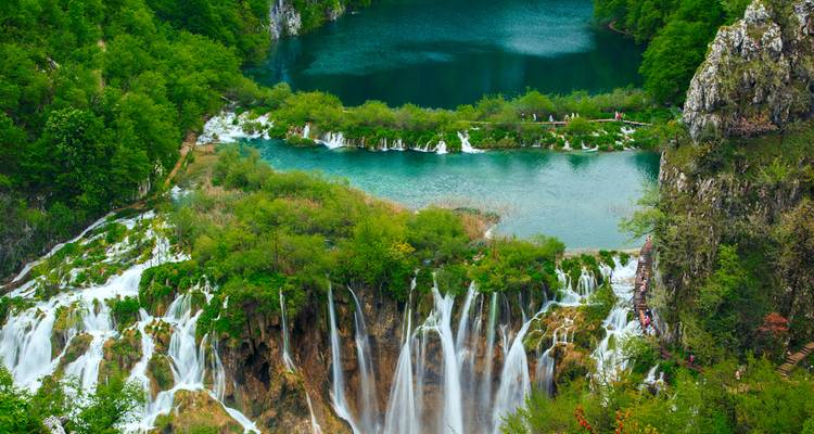 Lush landscape with cascading waterfalls and teal waters.