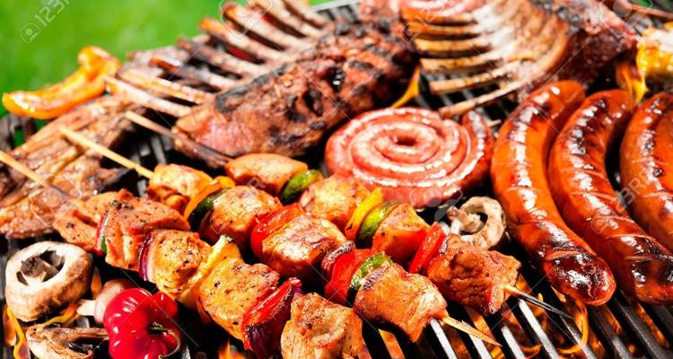 Verschillende gegrilde vlees- en groentesoorten op een barbecue.