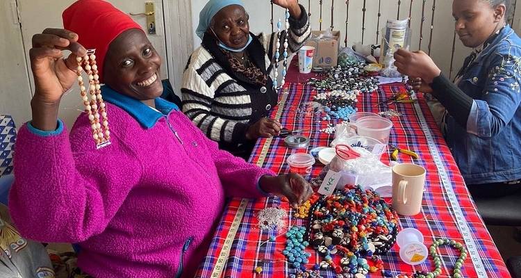 Vrouwen die glimlachen en kralenwerk maken aan een tafel.