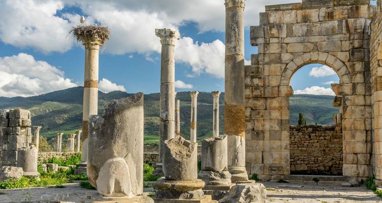 Antike römische Ruinen mit Säulen und Steinbauten unter einem blauen Himmel.