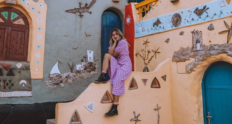 Frau posiert vor einer bemalten Wand in einem nubischen Dorf.