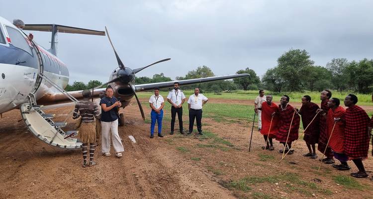 Grupo de personas reunidas cerca de una aeronave con bailarines locales.