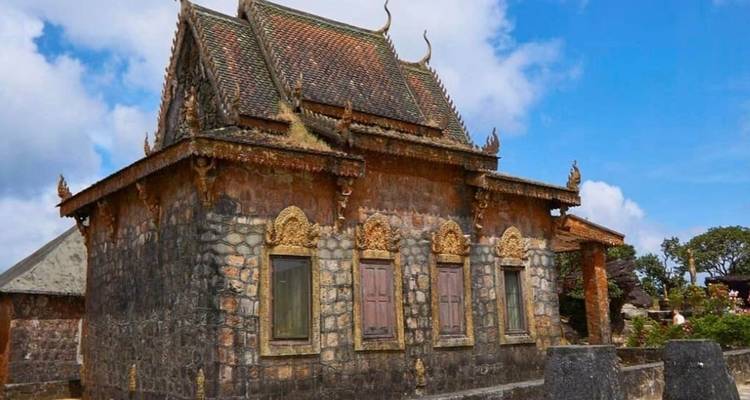 Eine kleine Tempelstruktur mit kunstvollen Schnitzereien unter einem blauen Himmel.