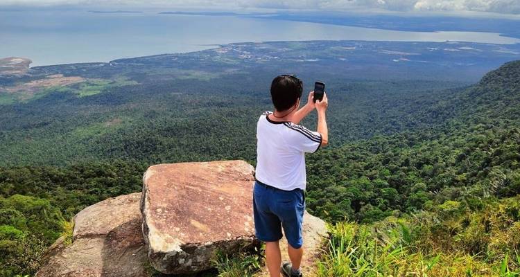 Eine Person, die auf einer Klippe mit weitem Ausblick ein Foto macht.