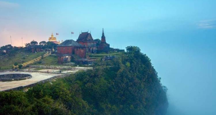 Ein historisches Gebäude am Rand einer nebligen Klippe.