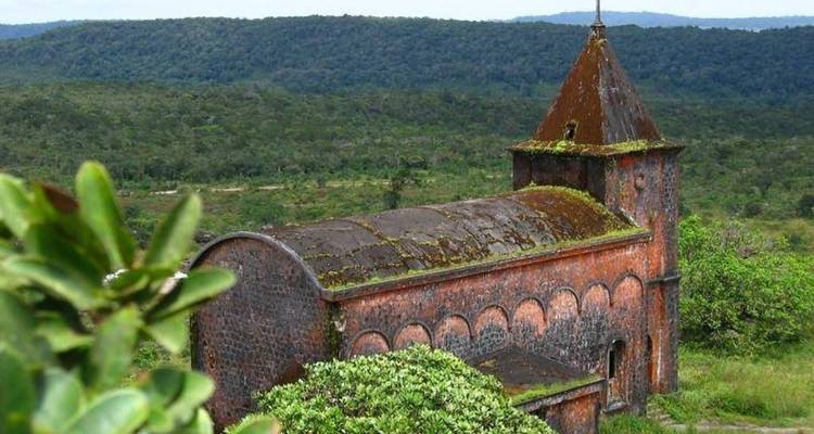 Eine alte Kirche umgeben von üppigem Wald.