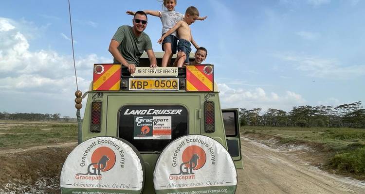 Family on top of a safari vehicle posing for a photo.