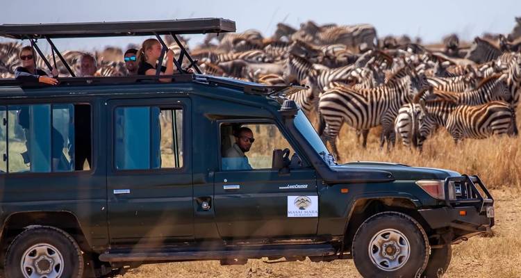 Safari vehicle near a herd of zebras in Kenya.