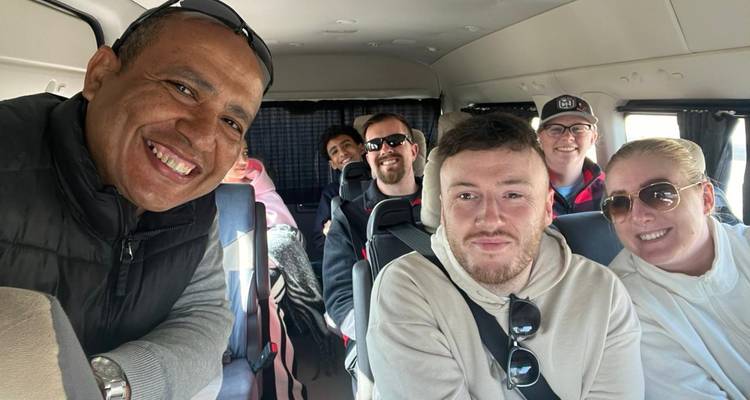 Los pasajeros sonrientes se sientan dentro de un minibús turístico listos para su excursión.