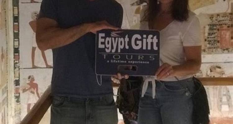 Twee mensen die een bord vasthouden met daarop 'Egypt Gift Tours' in een Egyptische tombe.