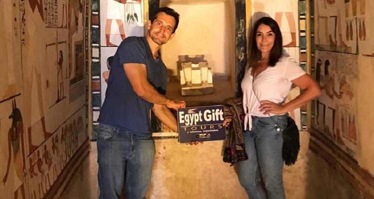 Twee mensen die poseren met een bord waarop 'Egypt Gift Tours' staat binnen een oude Egyptische site.