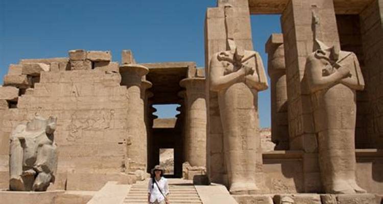 Persoon die loopt tussen oude Egyptische ruïnes met grote beelden.