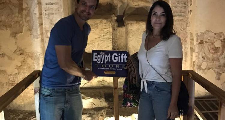 Twee mensen die een bord vasthouden met daarop 'Egypt Gift Tours' op een oude Egyptische locatie.
