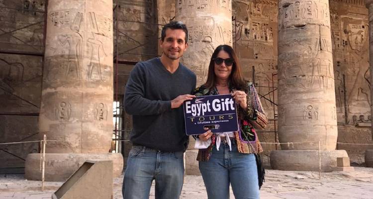 Couple holding a sign in front of ancient Egyptian pillars.