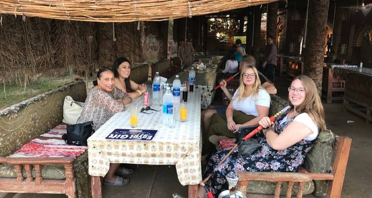 Groep vrouwen zittend aan een buiteneetgelegenheid.