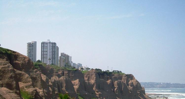 Küstenklippen mit Gebäuden darauf und dem Meer dahinter.