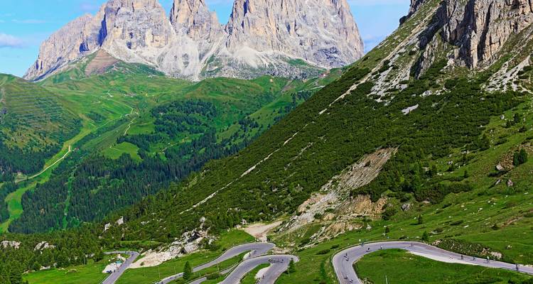 Sommets montagneux avec routes sinueuses et verdure.