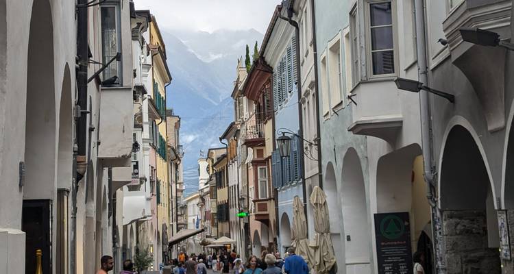 Rue animée bordée d'arches avec des gens qui se promènent.