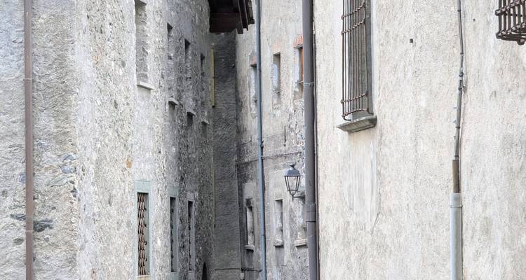 Ruelle étroite entre de hauts bâtiments en pierre.