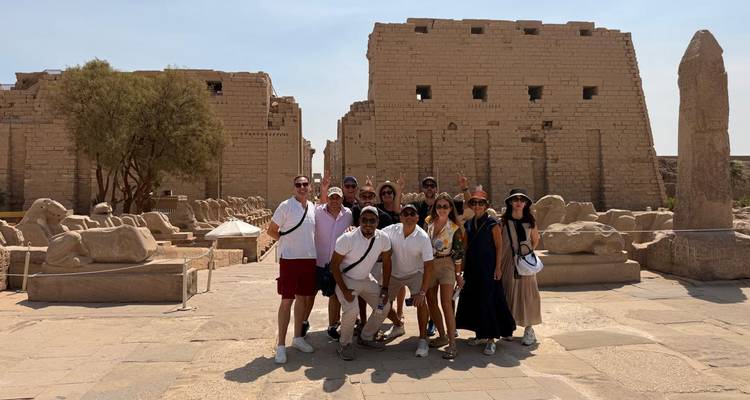 Toergroep poseert op de open binnenplaats van Karnak met verspreide oude beelden rondom.
