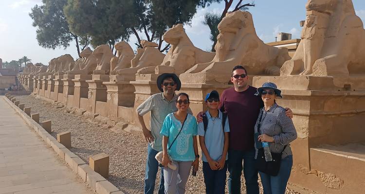 Familie die staat naast de avenue van ramshoofdige sfinxen bij de Karnak Tempel.