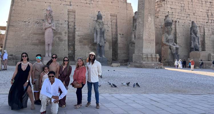 Groep poseert voor de standbeelden van de Luxor Tempel, een paar duiven op de stenen binnenplaats.