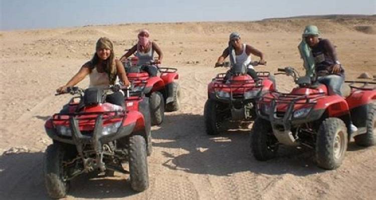 Group of friends riding ATVs across a desert setting.