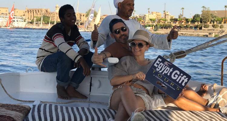 Groupe de personnes sur un bateau avec un panneau « Egypt Gift Tours » près d'une rivière.