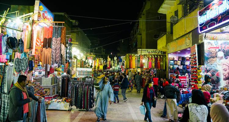 Ein lebendiger Nachtmarkt mit Menschen beim Einkaufen und bunten Ständen.