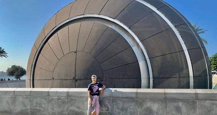 Personne debout devant une grande structure moderne ronde.