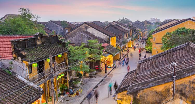 Historische Stadt mit gelben Gebäuden und gehenden Menschen.