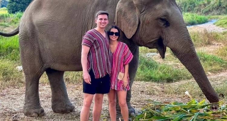 Paar posiert mit einem Elefanten und trägt traditionelle Kleidung.