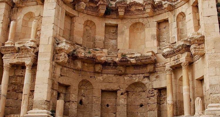 Oude stenen amfitheater ruïnes met bogen en zuilen in zicht.
