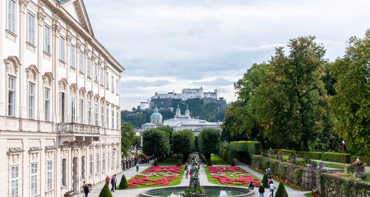 Mirabell Gardens with vibrant flower beds and Salzburg Fortress rising on the hill beyond.