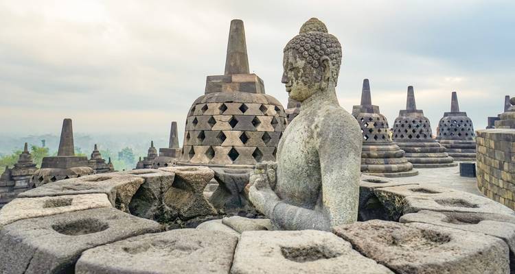 Borobudur-Tempel mit einer steinernen Buddha-Statue im Vordergrund.