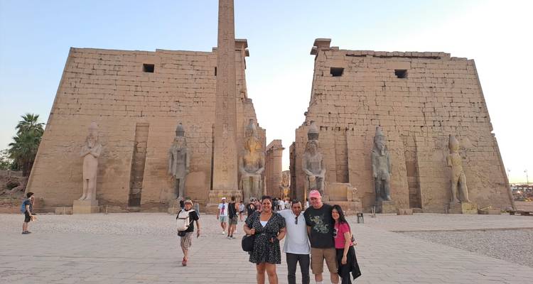 Los viajeros posan en los pilones monumentales del Templo de Luxor cerca de la luz del atardecer.
