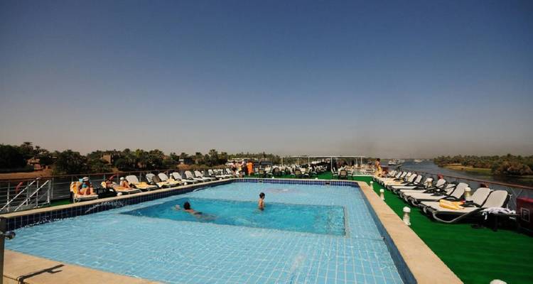 Piscina al aire libre en la cubierta solar de un crucero por el Nilo con tumbonas y pasajeros disfrutando de la vista.