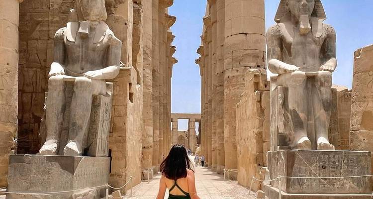 Person, die durch einen altägyptischen Tempel mit großen Statuen auf beiden Seiten geht.