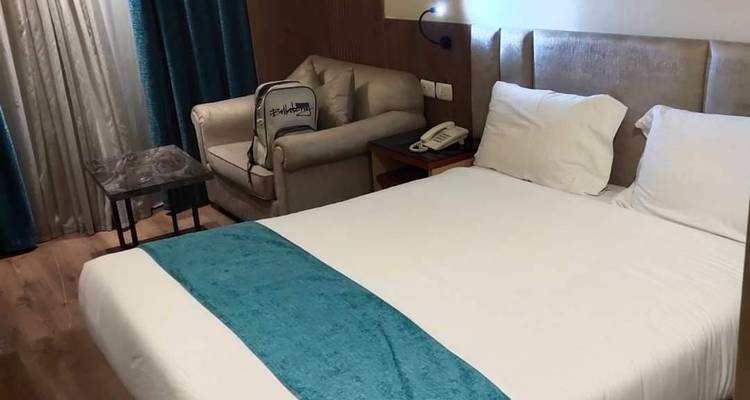 Innenraum eines modernen Hotelzimmers mit einem Doppelbett und einer Sitzecke.